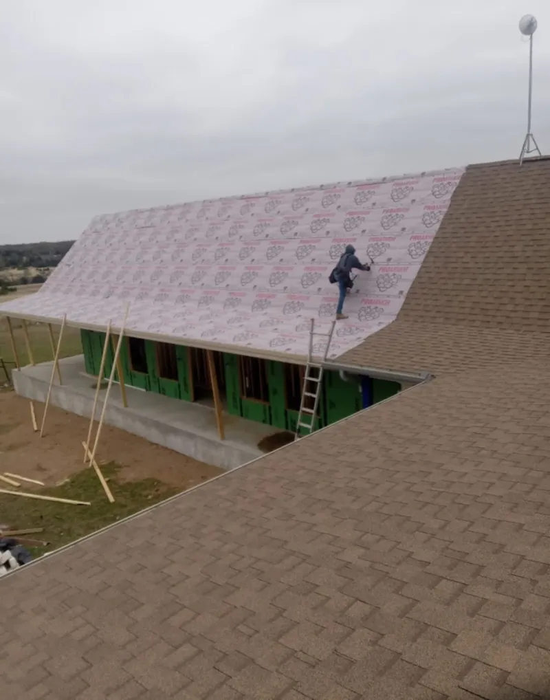 Worker preparing underlayment for a metal roof installation in Gilmer
